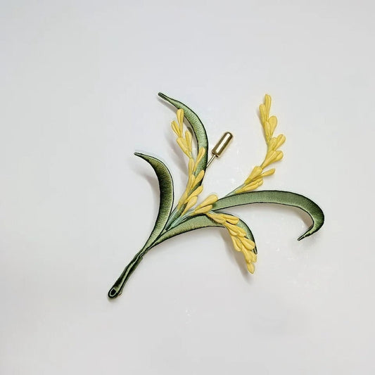 Handcrafted Chanhua wheat ear brooch featuring yellow thread-wrapped grains and green leaves on a white background.