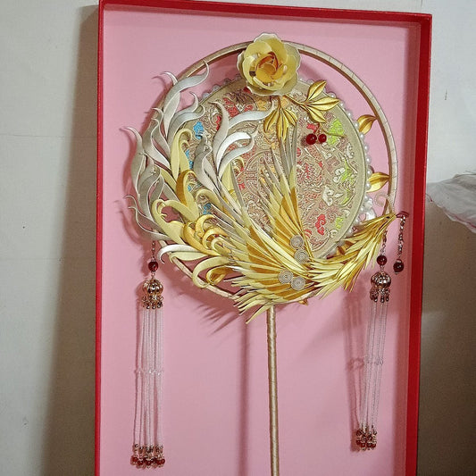 Luxury handcrafted Chanhua thread-wrapped bridal fan featuring a golden phoenix, yellow rose, and elegant beaded tassels against a pink background.