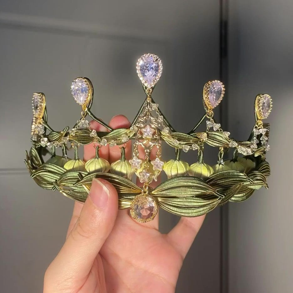 Handheld closeup of a handmade Chanhua lily of the valley crown with layered green leaves and sparkling crystal embellishments