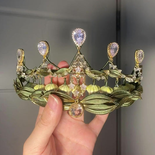 Handheld closeup of a handmade Chanhua lily of the valley crown with layered green leaves and sparkling crystal embellishments