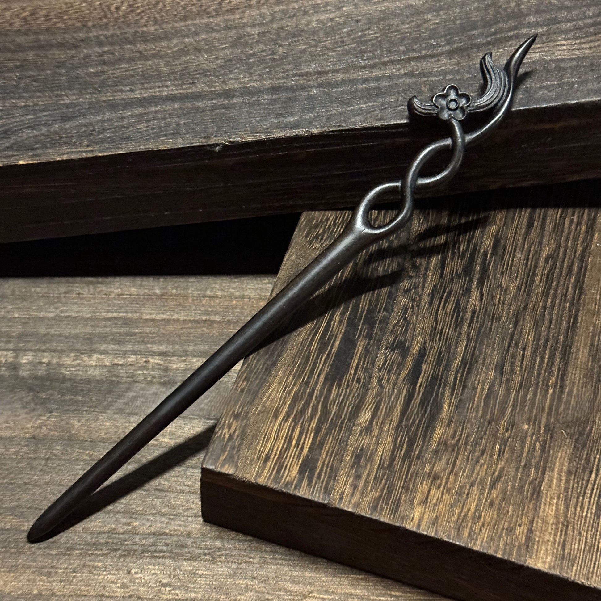 Natural African Blackwood hair stick with 18cm secluded orchid carved design on wooden background.