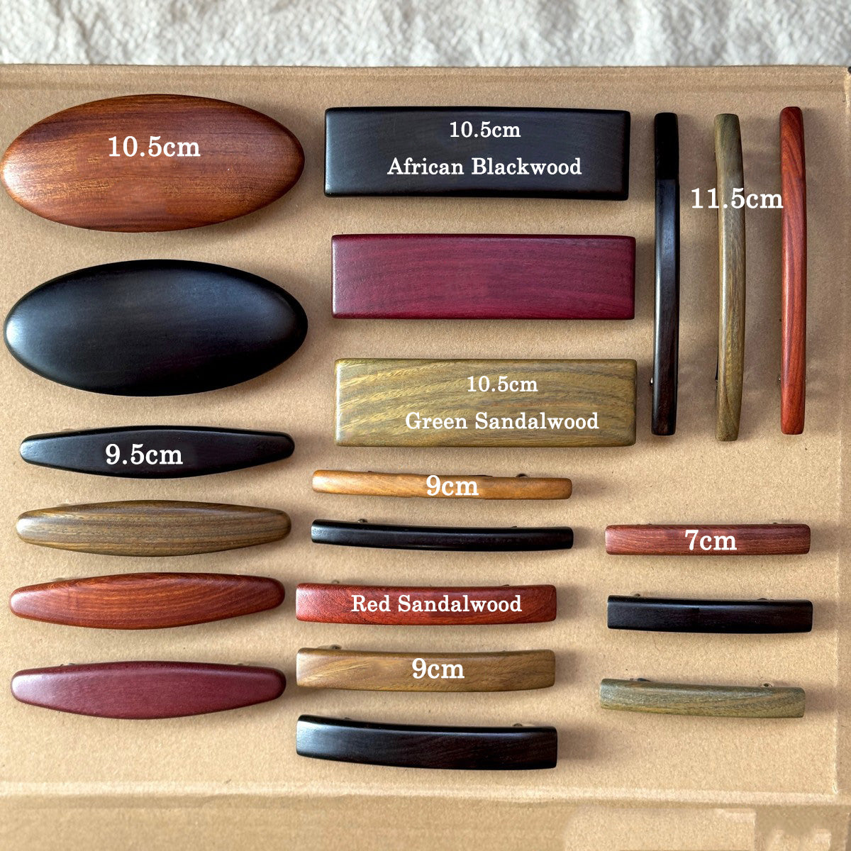 Array of polished wood barrettes featuring oval, rectangular, and curved designs in black, red, and brown tones