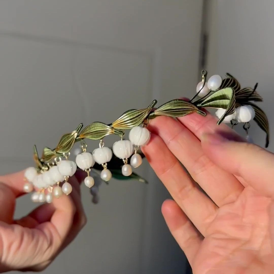 Handcrafted Chanhua headband featuring white thread-wrapped Lily of the Valley flowers and green leaves with pearl accents.