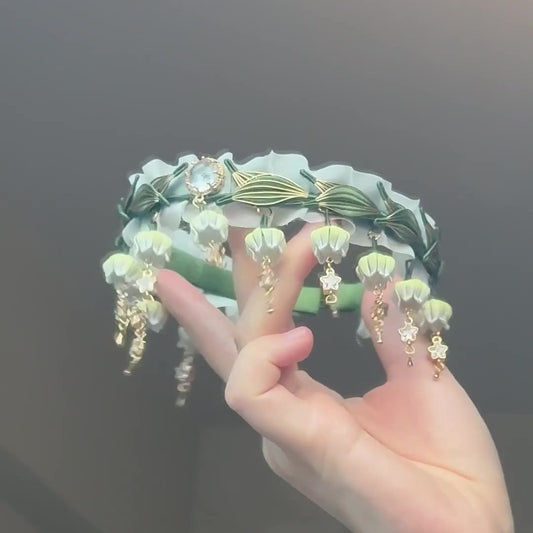 Handcrafted Chanhua choker necklace featuring thread-wrapped Lily of the Valley flowers and green leaves on a white ruffled ribbon.