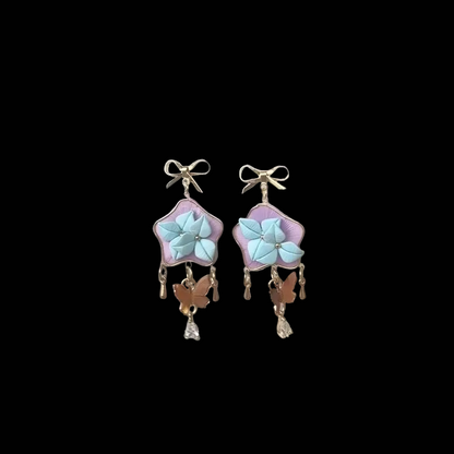 Handcrafted star-shaped Chanhua earrings with light blue thread-wrapped flowers, gold bows, and butterfly charms.