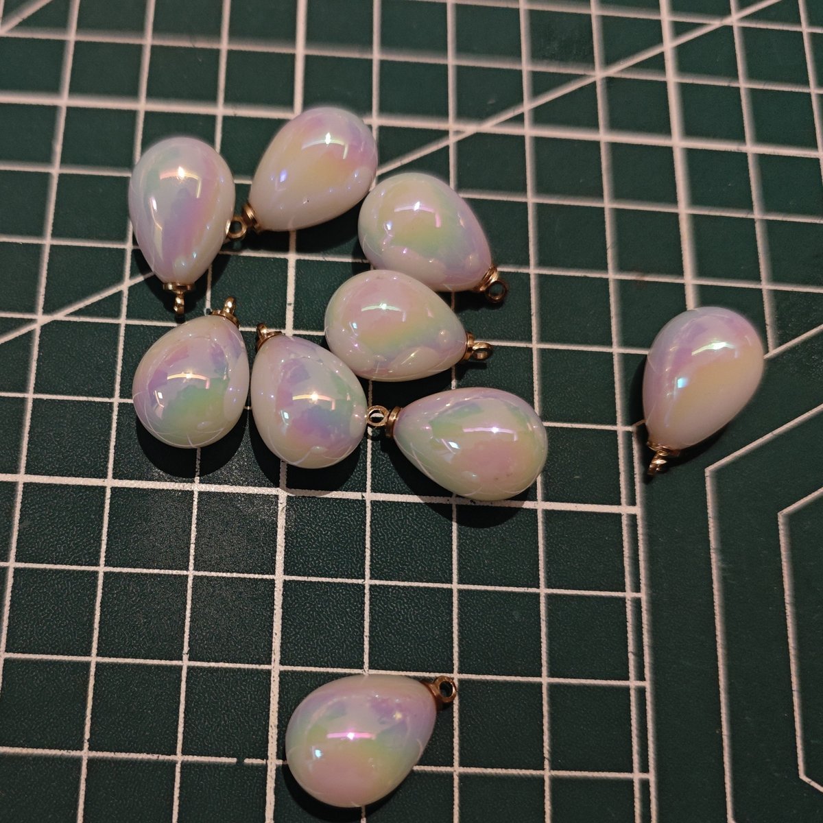 Collection of white iridescent mermaid tear drop charms for jewelry making, a necessary DIY craft supply.