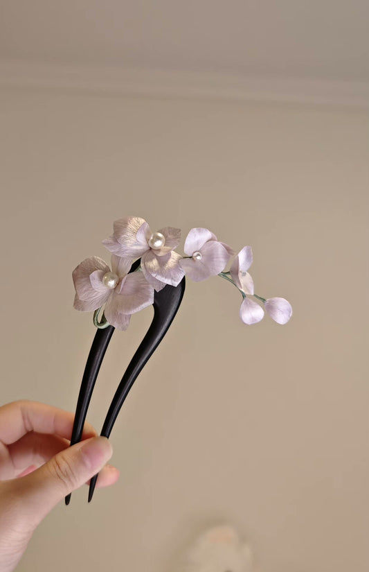 Handmade Ronghua orchid hair accessory with silk flowers and pearls held in a hand
