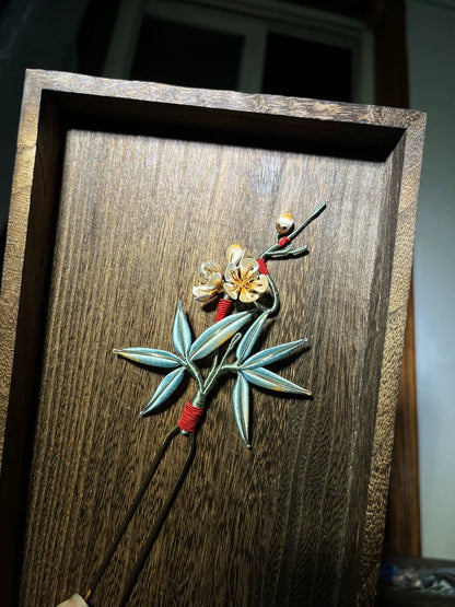 A handmade Chanhua hairpin with bamboo and plum blossom design on a wooden background-4