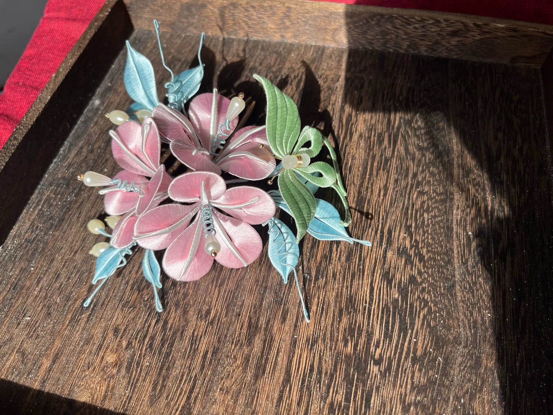 A handmade Chanhua morning glory hairpin with pink flowers and blue - green leaves on a wooden tray