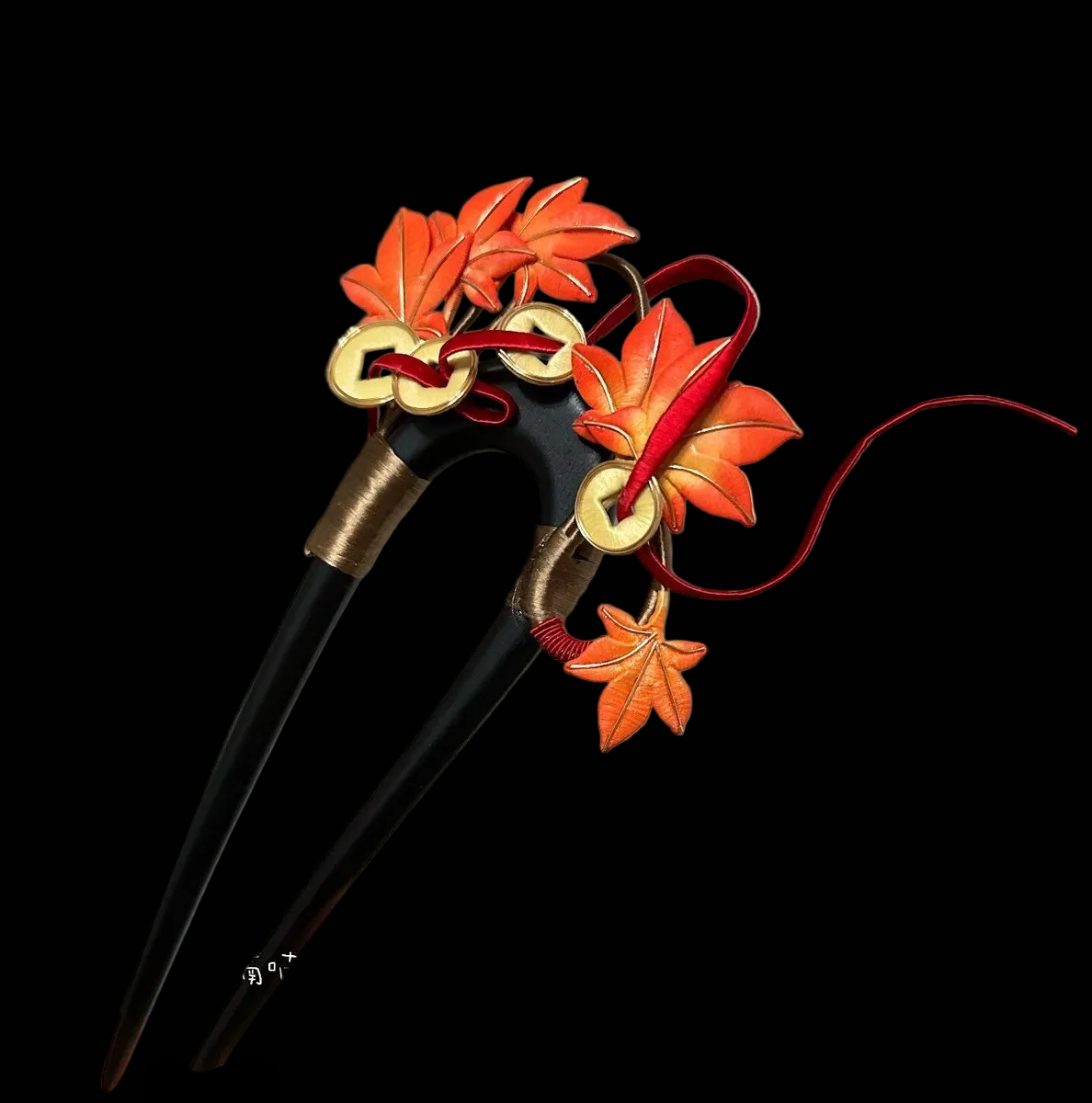 Handcrafted Chanhua hair fork featuring orange thread-wrapped maple leaves and traditional copper coins on a dark base.