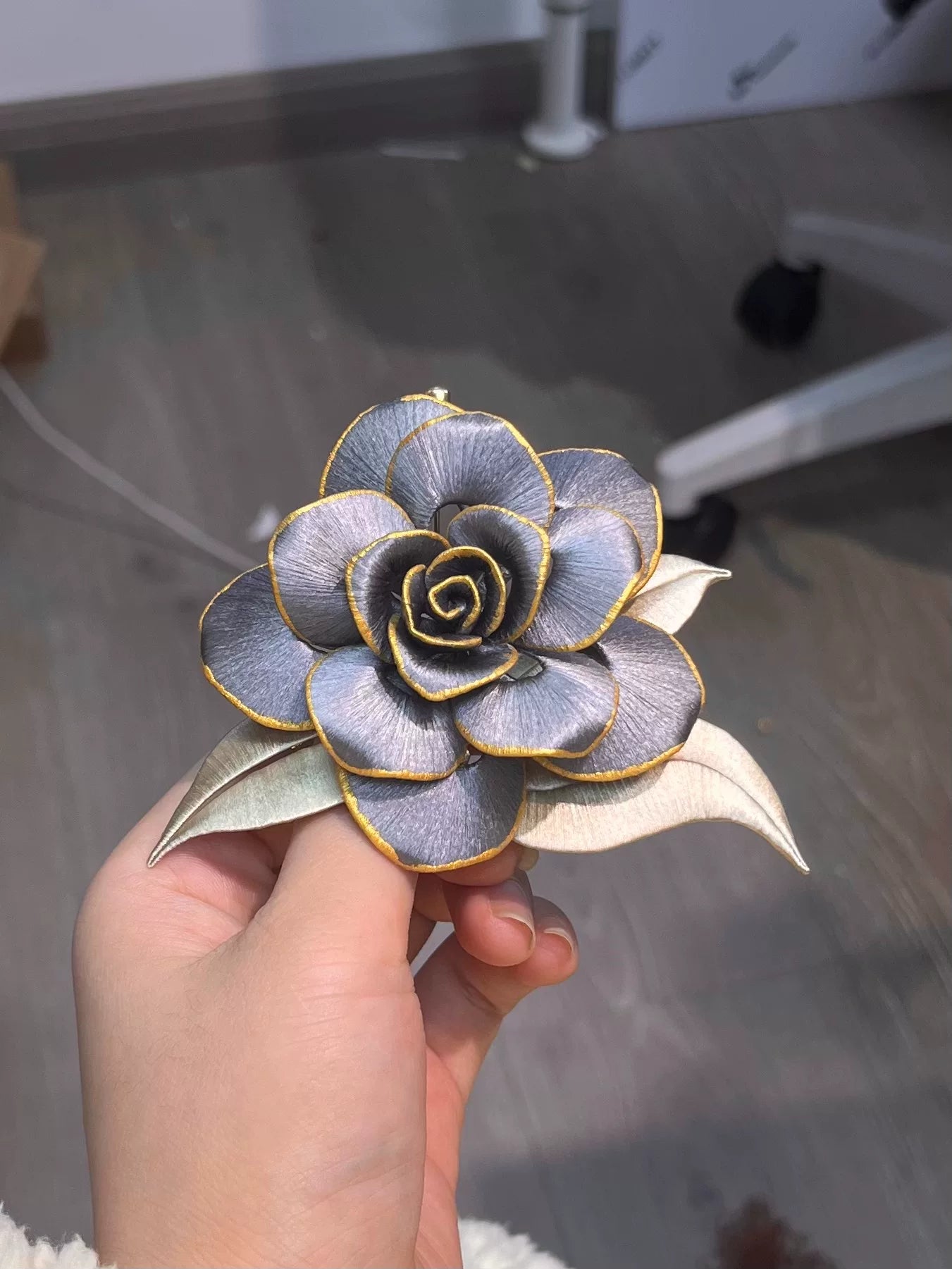 Handmade Chanhua brooch in blue and gold tones, held by a hand-4