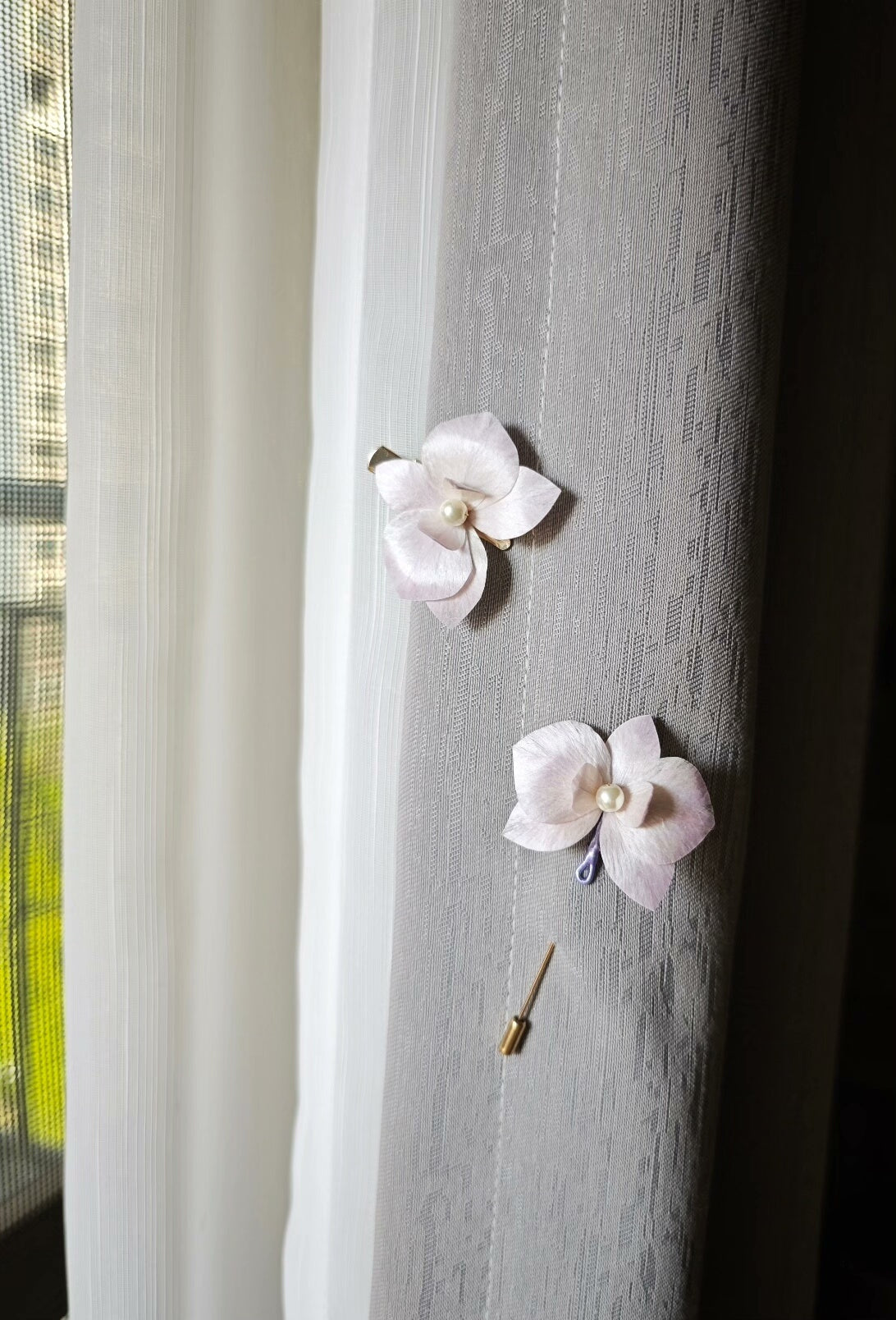 Two handmade Ronghua floral hair accessories with a butterfly - orchid design attached to a curtain