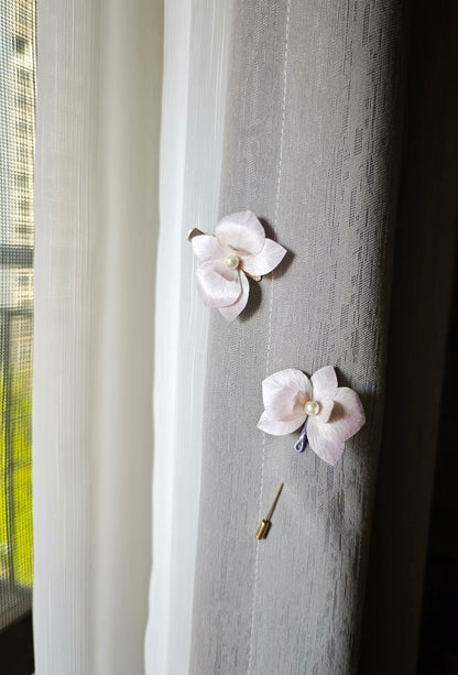 Two handmade Ronghua floral hair accessories with a butterfly - orchid design attached to a curtain