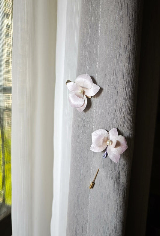 Two handmade Ronghua floral hair accessories with a butterfly - orchid design attached to a curtain