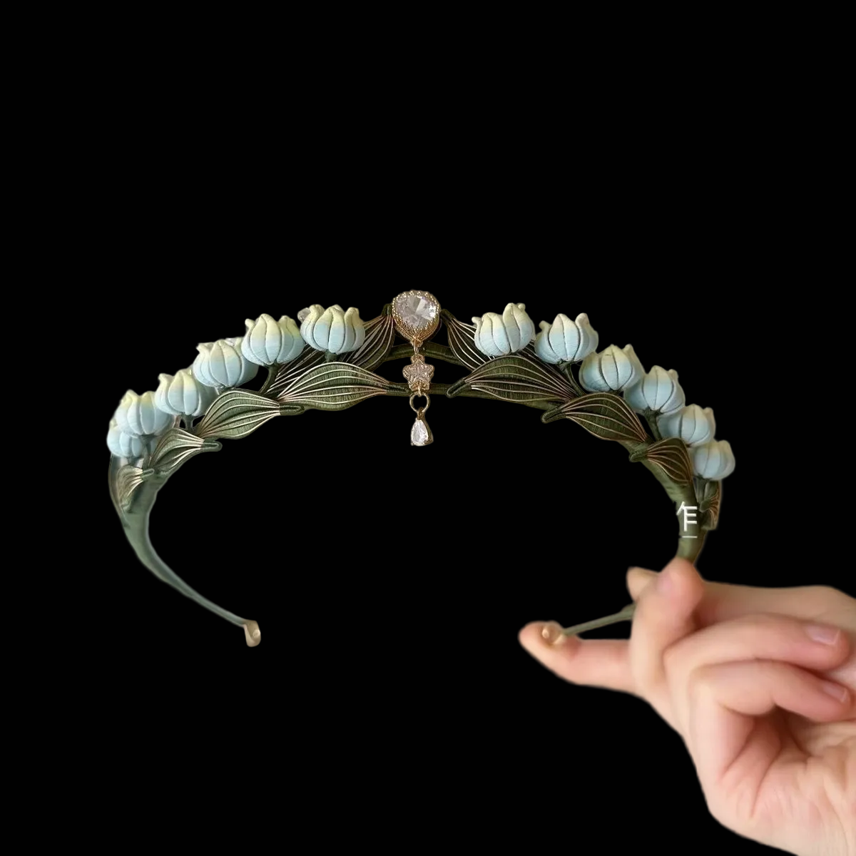Handcrafted Lily of the Valley Chanhua crown featuring light blue thread-wrapped flowers and green leaves with a central crystal pendant.
