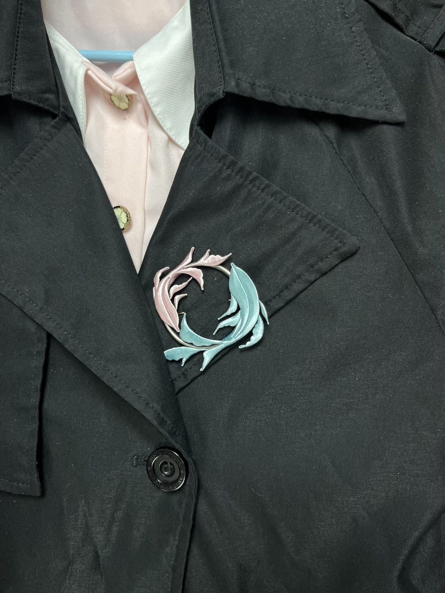 A handmade Chanhua Qiyu little fish brooch on a black coat