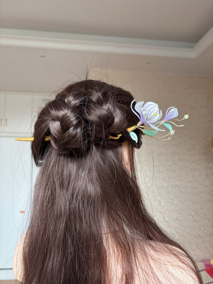 A handmade Chanhua magnolia hairpin with purple flowers and green leaves on a wooden stem.-5