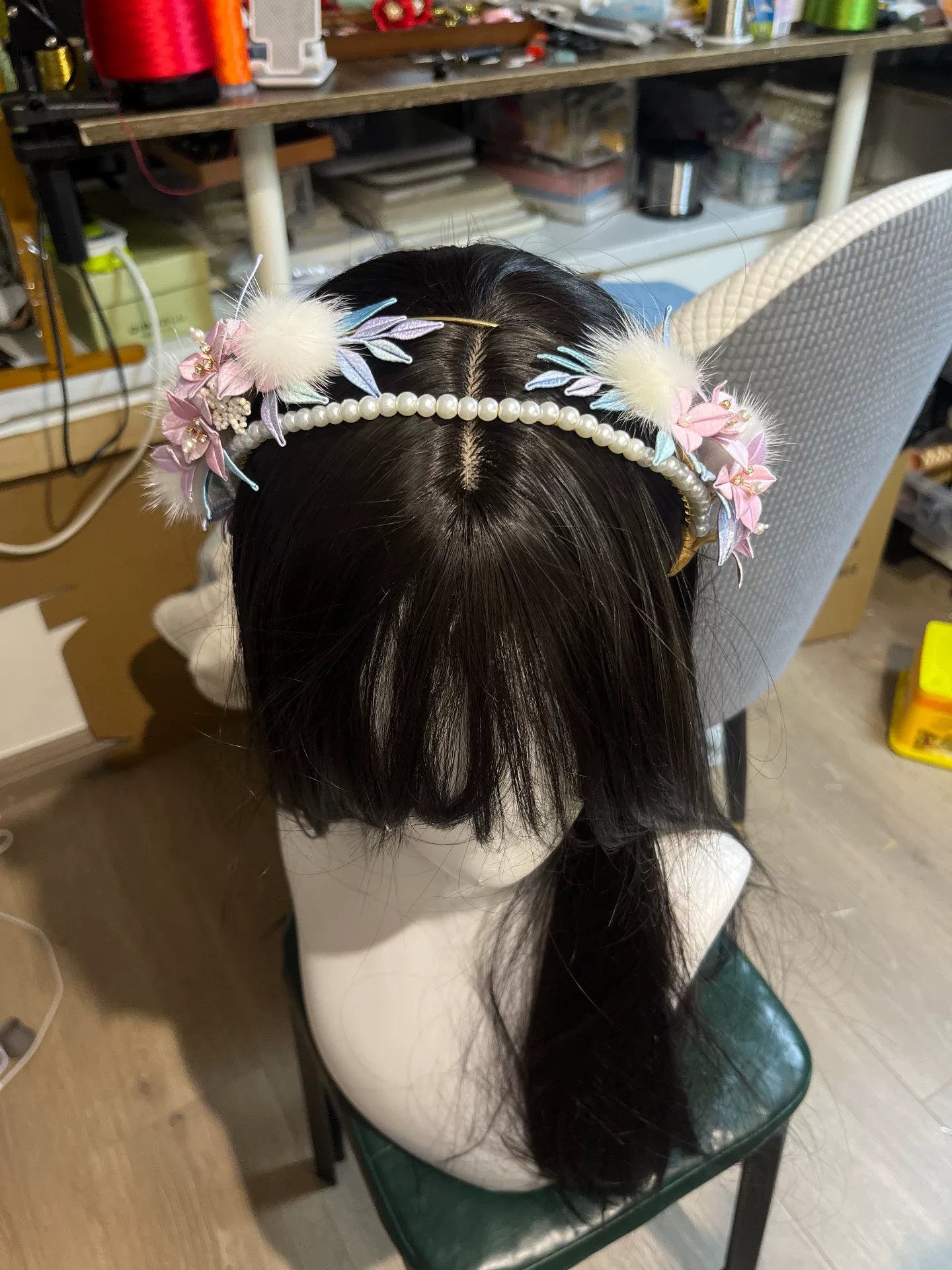 A handmade Chanhua orchid headband with pink flowers, white feathers, and pearls on a mannequin's head-4