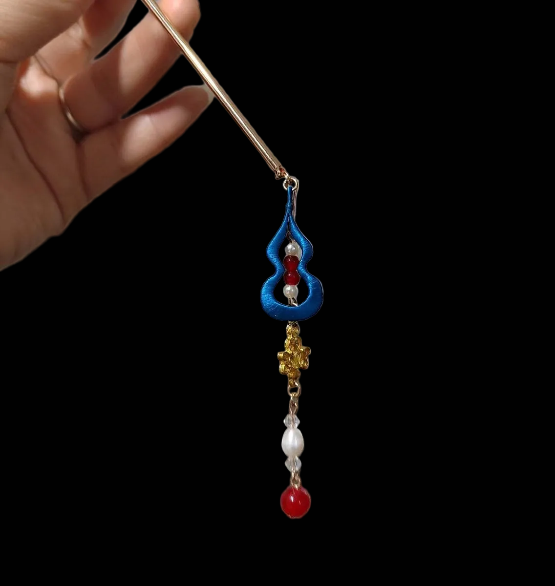 Close-up of a handcrafted Chanhua thread-wrapped blue gourd hairpin with red beads and a pearl-accented tassel.