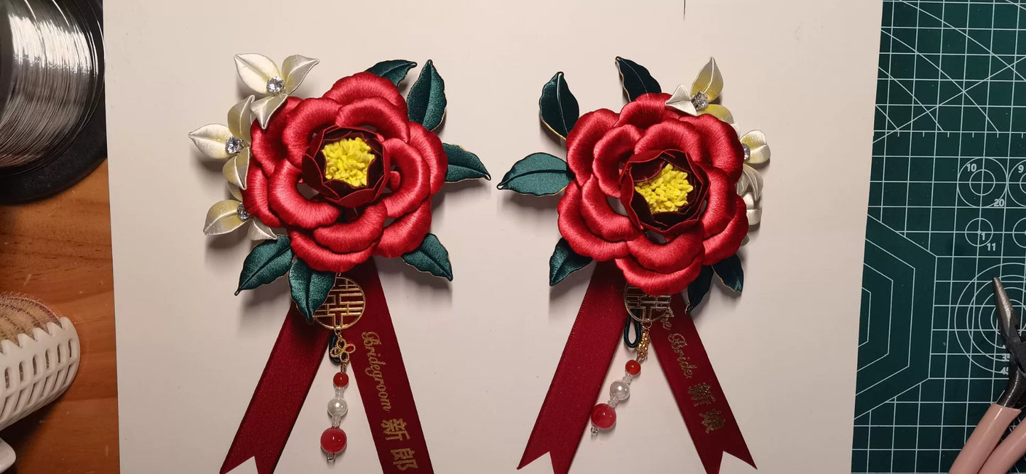Two red handmade Chanhua bridal boutonnieres with customizable ribbons on a red background-3