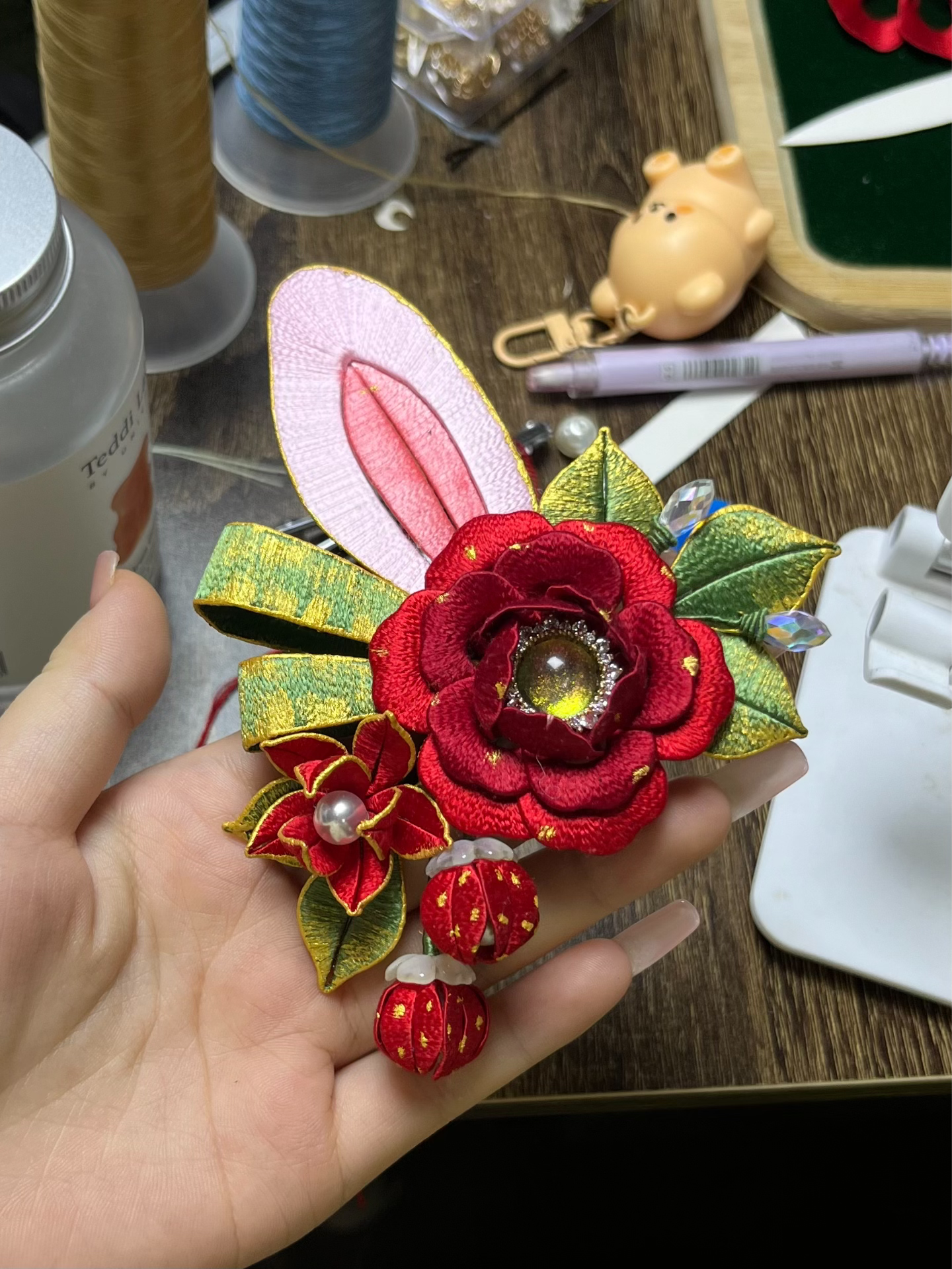 A pair of handmade Chanhua Christmas - style bunny - ear hair clips with red flowers and green leaves, on a mannequin's head-3