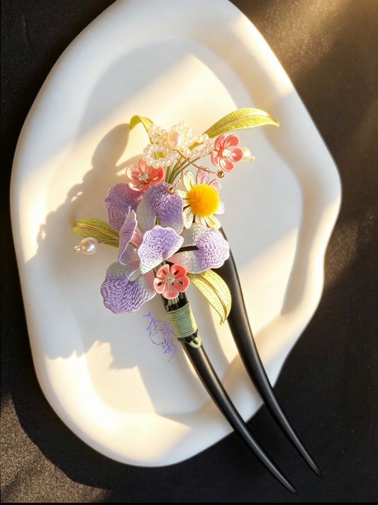 A handmade Chanhua iris hairpin with colorful flowers and leaves on a white plate