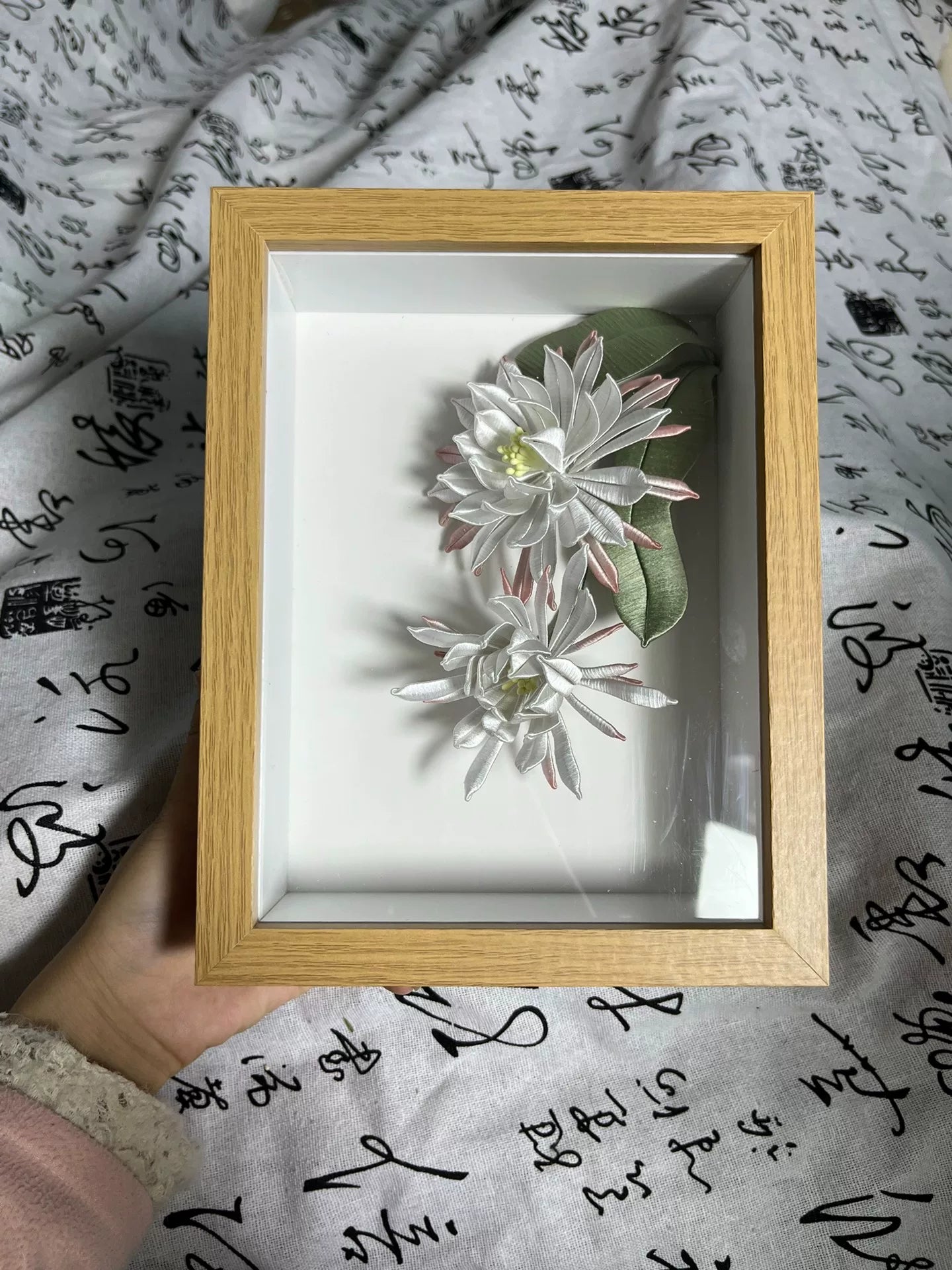 A handmade Chanhua table display in a wooden box with white and pink petals and green leaves-4