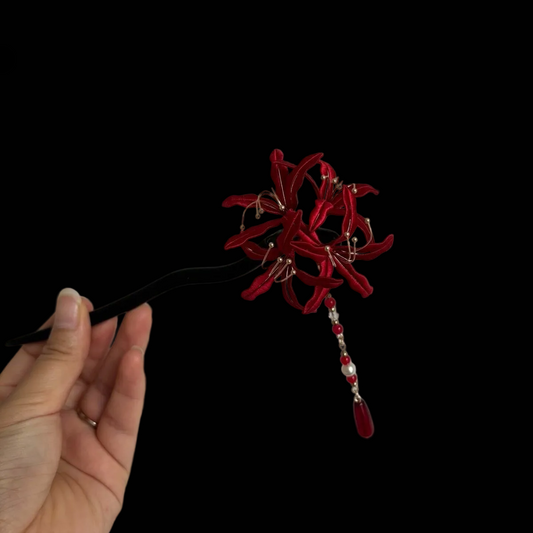 Close-up of an blue and red Chanhua thread-wrapped floral hair accessory with pearl accents.