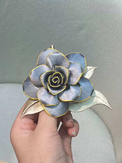 Handmade Chanhua brooch in blue and gold tones, held by a hand-3
