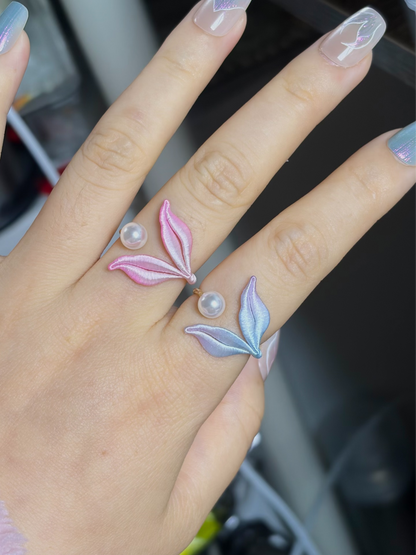 A hand wearing a blue mermaid tail ring and holding a blue mermaid tail necklace-6
