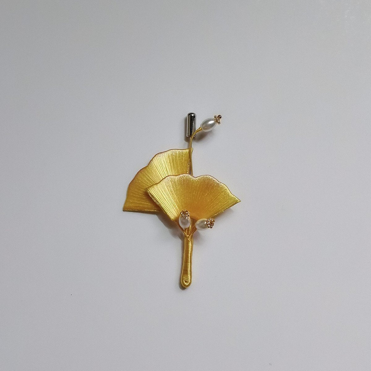 A traditional Chinese thread-wrapped (Chanhua) golden ginkgo leaf pin on a plain background, showing artisanal 3D textures.