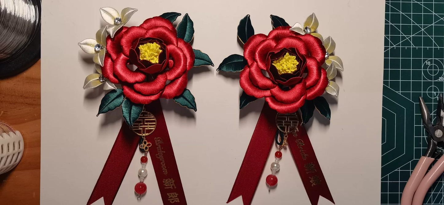 Two red handmade Chanhua bridal boutonnieres with customizable ribbons on a red background-2