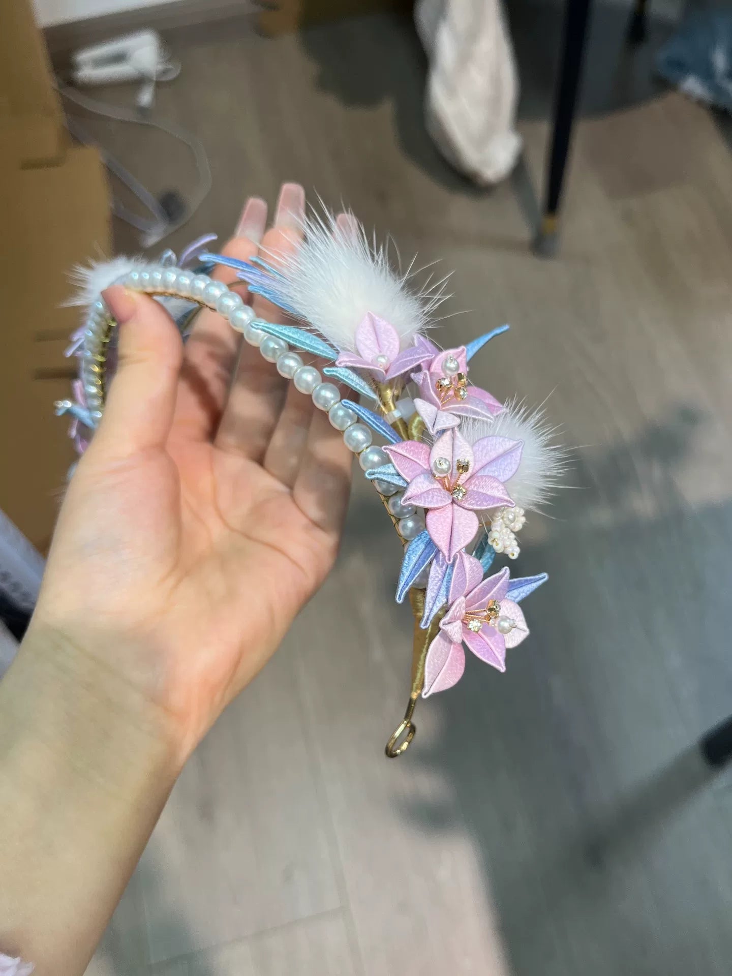 A handmade Chanhua orchid headband with pink flowers, white feathers, and pearls on a mannequin's head-6