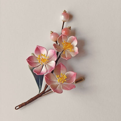 Luxury 3D embroidery floral pin depicting a branch of peach flowers made with intricate artisanal thread-wrapping techniques.