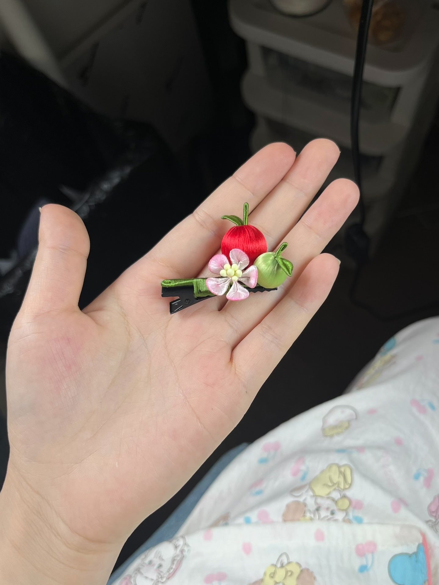 A hair clip with red and green apples and a pink flower on black hair-3