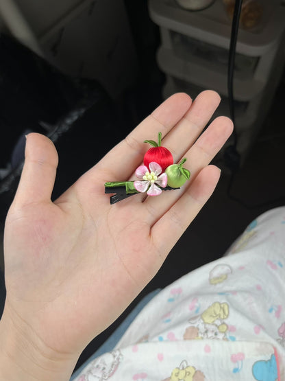 A hair clip with red and green apples and a pink flower on black hair-3