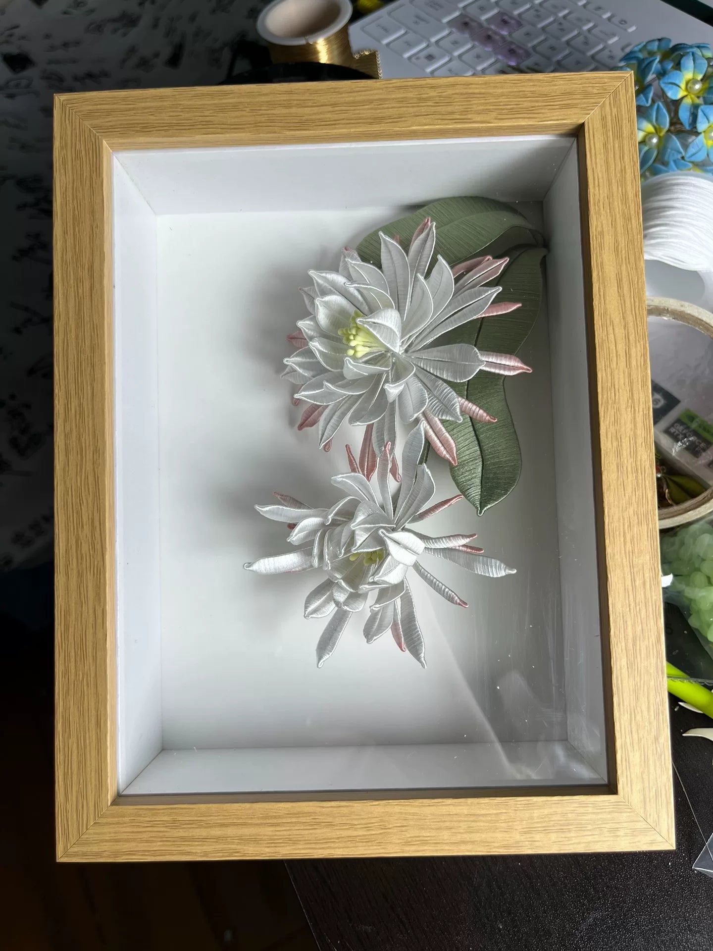 A handmade Chanhua table display in a wooden box with white and pink petals and green leaves-2