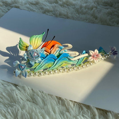 Sunlit handmade Chanhua Thousand Miles of Rivers and Mountains hair crown placed on a white card over fluffy rug