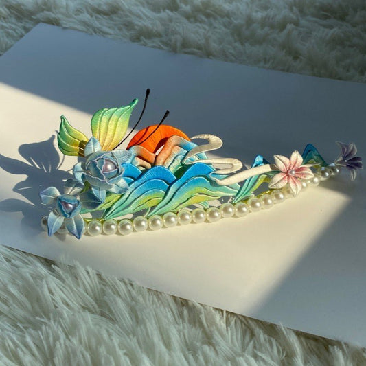 Sunlit handmade Chanhua Thousand Miles of Rivers and Mountains hair crown placed on a white card over fluffy rug