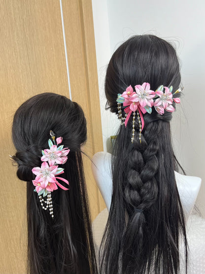 A handmade Chanhua lily hairpiece in pink with leaves and dangling chains on black hair