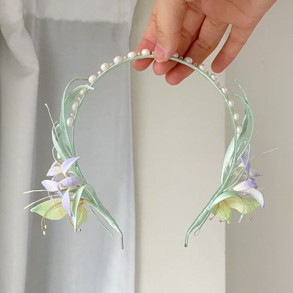 Hand holding a handmade Chanhua little orchid hairband with fresh pastel purple and green floral details