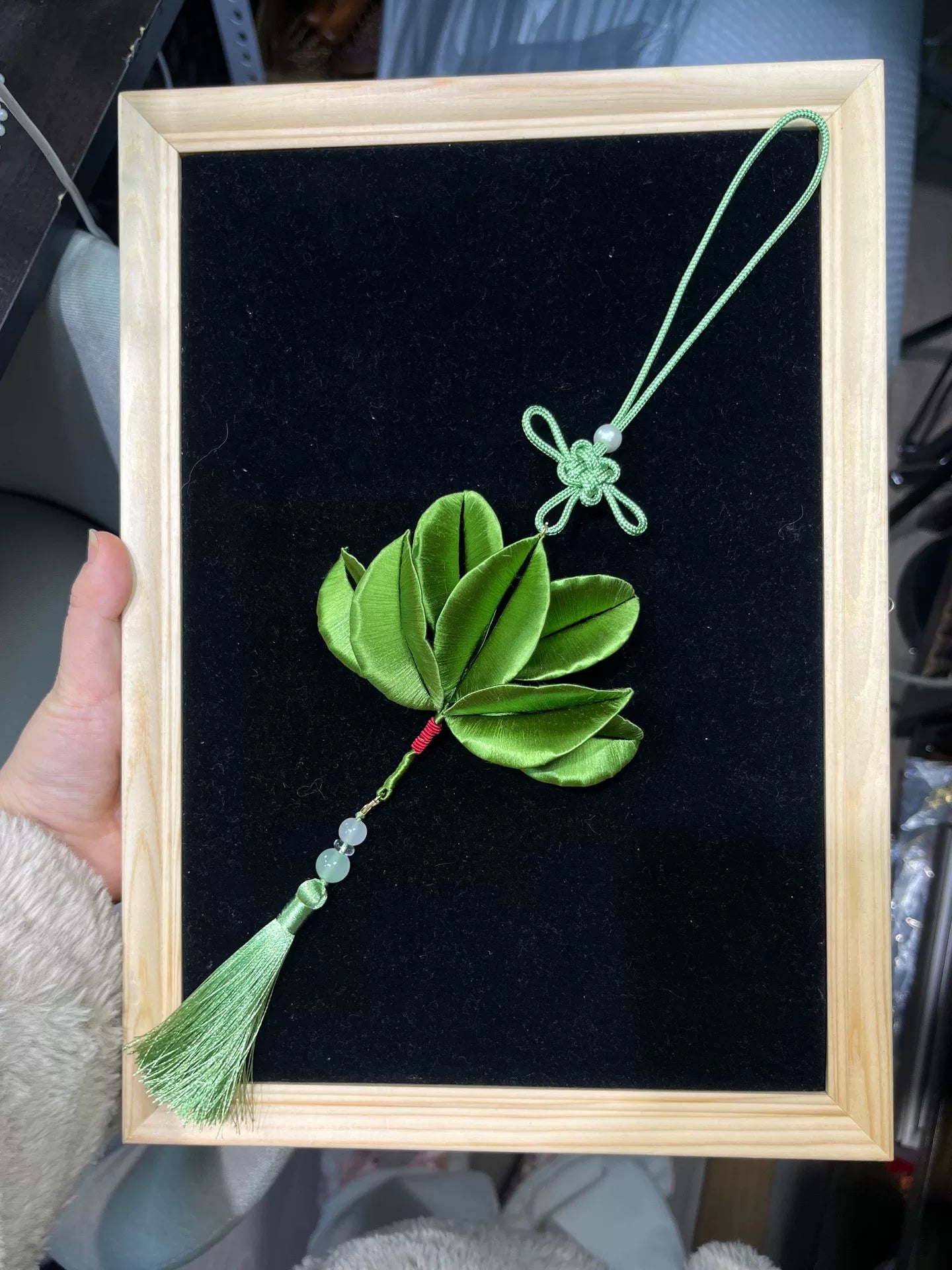 A handmade Chanhua pomelo leaf car hanger with green leaf, knot, and tassel