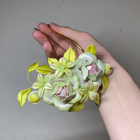 Hand holding a handmade Chanhua green spring bud floral hair pin with yellow leaves