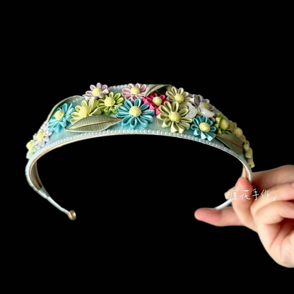 Handcrafted daisy Chanhua headband featuring colorful thread-wrapped flowers and green leaves on a light blue base.