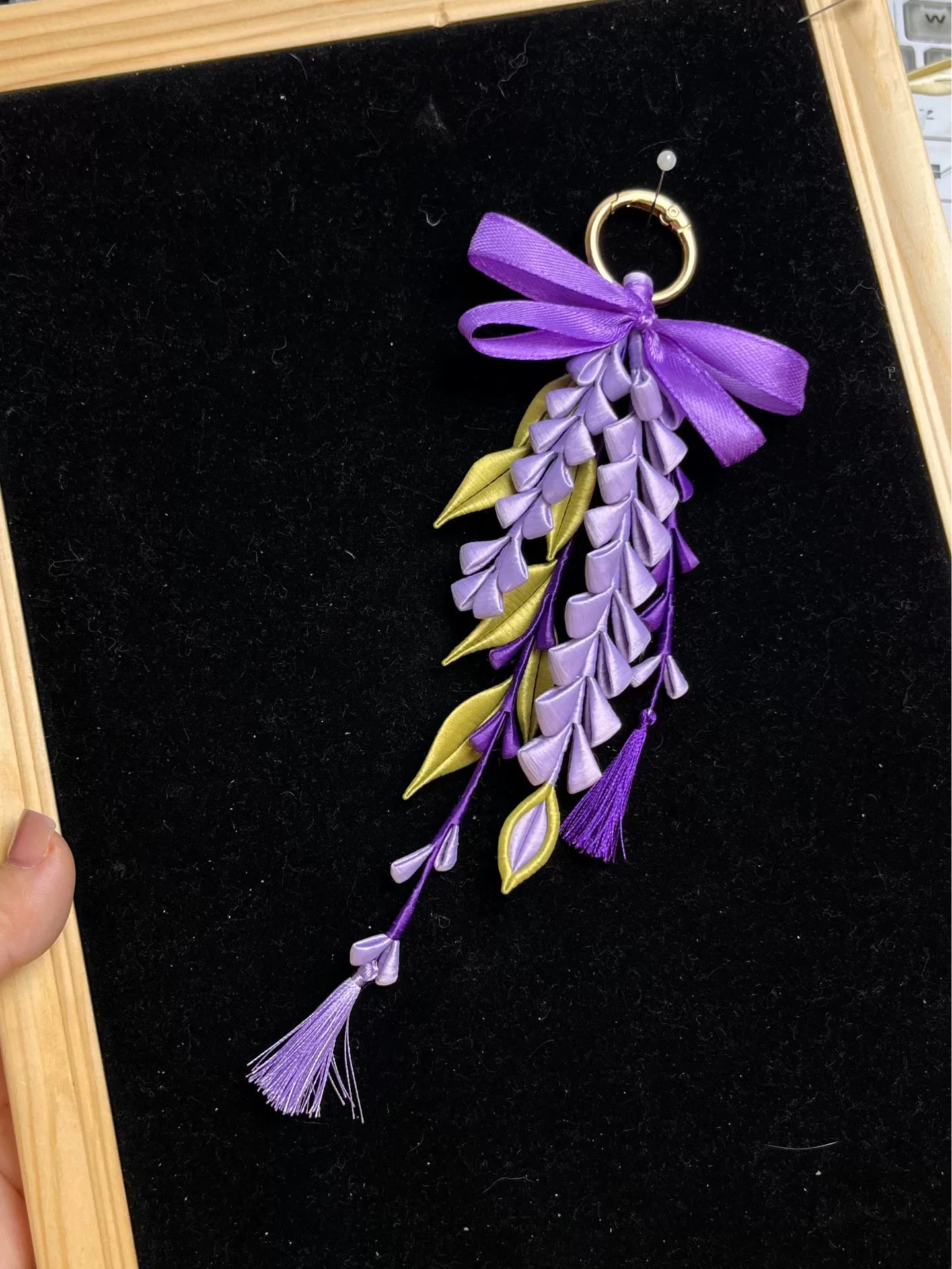 A hand - held purple wisteria keychain with a golden ring and decorative bow-4
