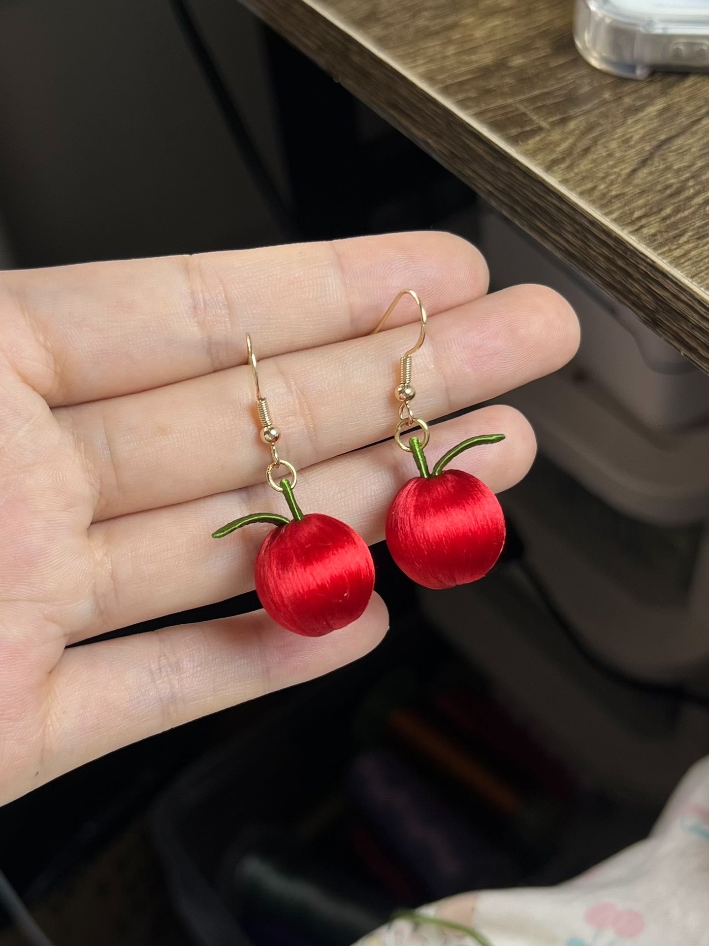 A pair of handmade Chanhua apple earrings worn on an ear-2