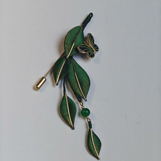 Handcrafted Chanhua brooch featuring vibrant green thread-wrapped leaves, a small butterfly accent, and a dangling green bead.