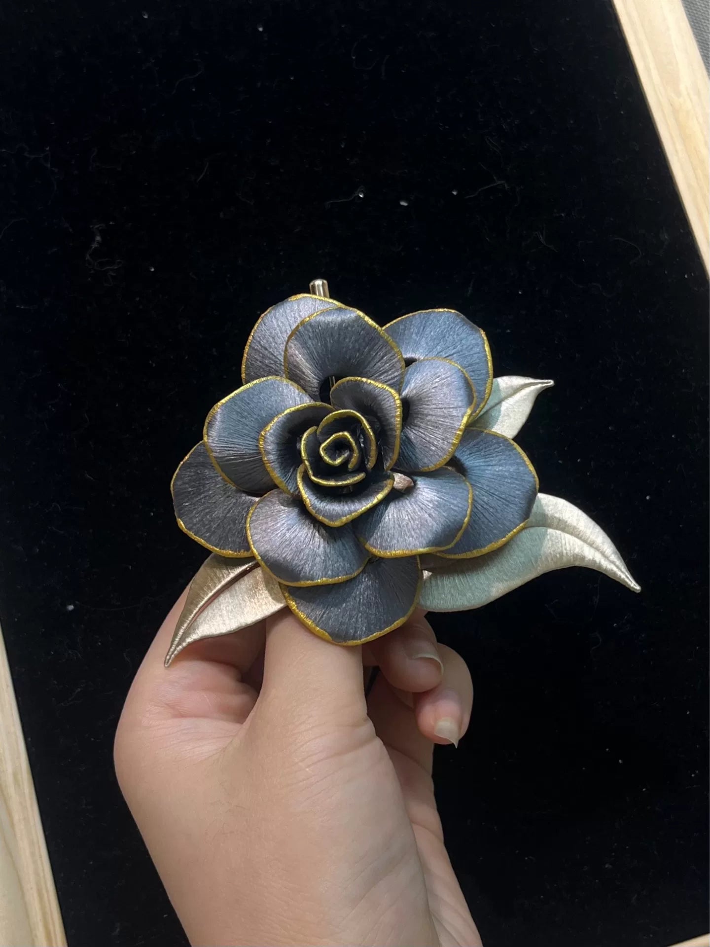 Handmade Chanhua brooch in blue and gold tones, held by a hand-2