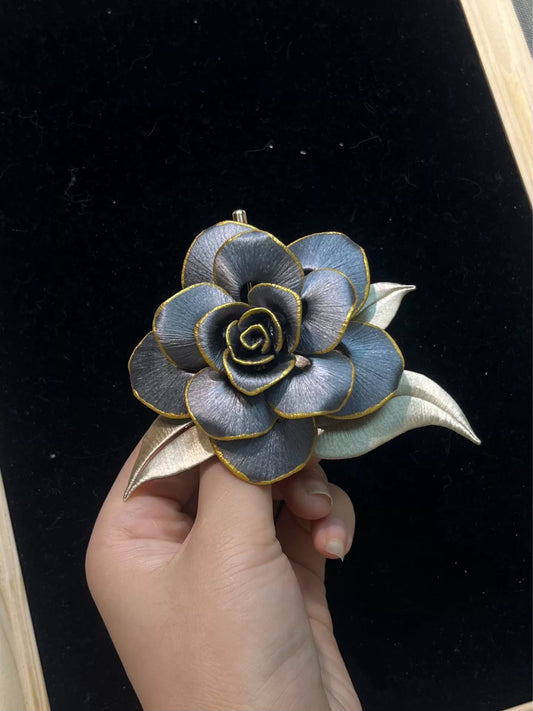 Handmade Chanhua brooch in blue and gold tones, held by a hand-2