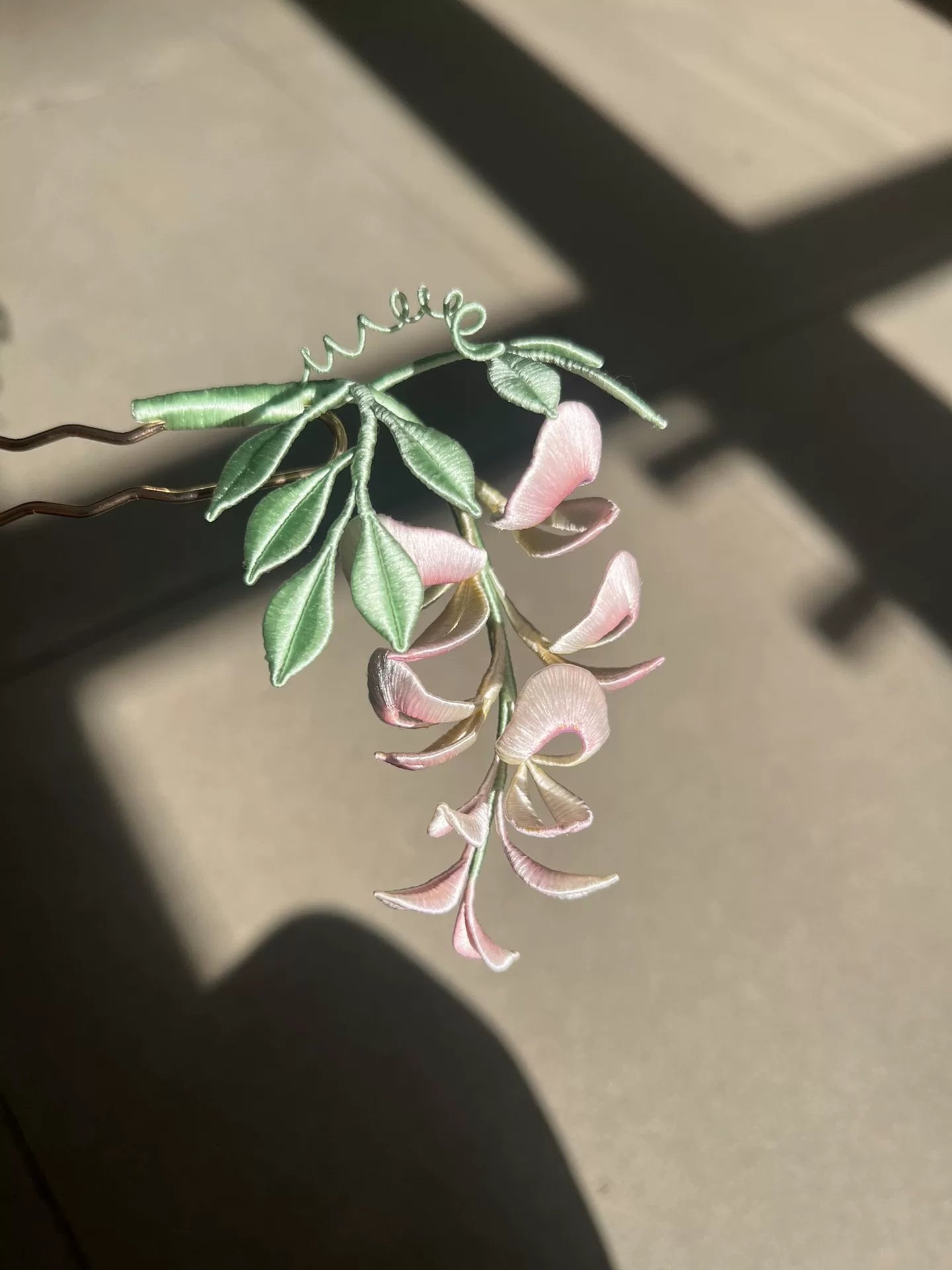 A handmade Chanhua wisteria flower accessory with pink petals and green leaves